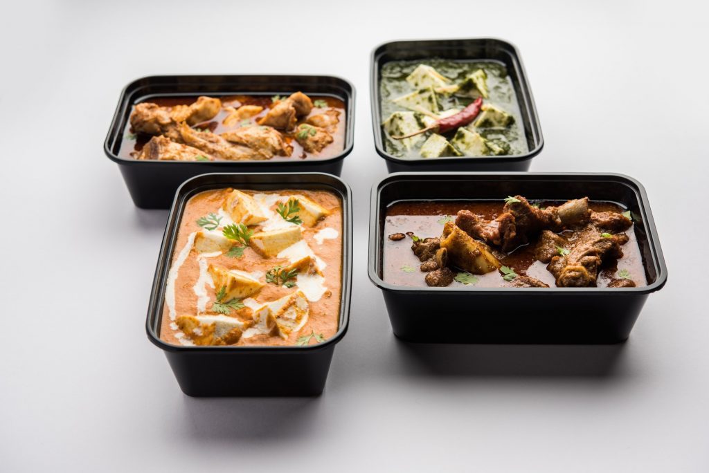 Online food delivery concept for Indian Restaurant showing plastic containers with food