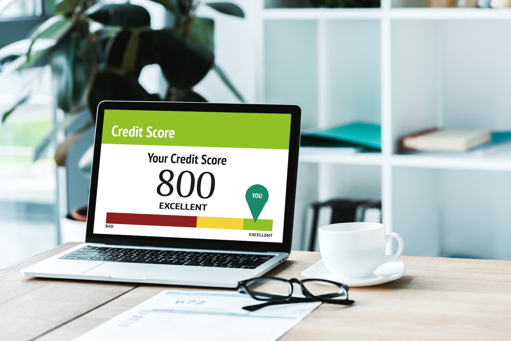 cup of coffee near laptop with credit score lettering and numbers on screen