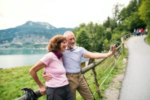 Senior pensioner couple hikers standing in nature, taking selfie.